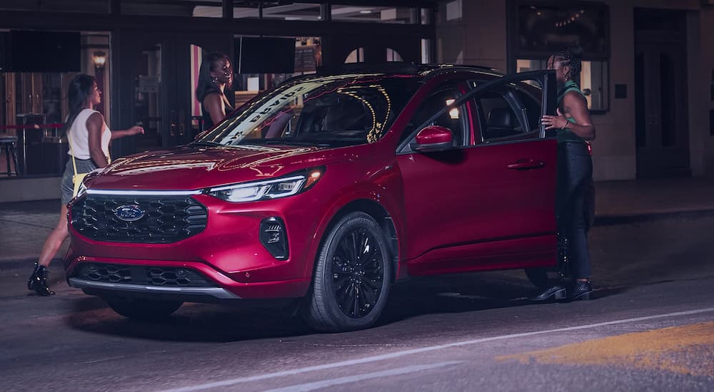 Two people exiting a parked red 2025 Ford Escape.