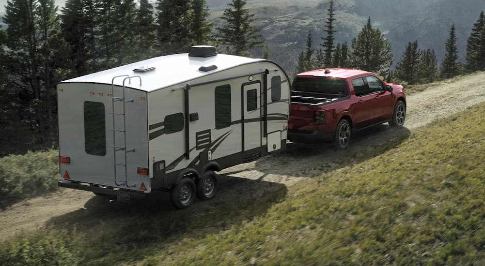 A red 2025 Ford Maverick towing a trailer.