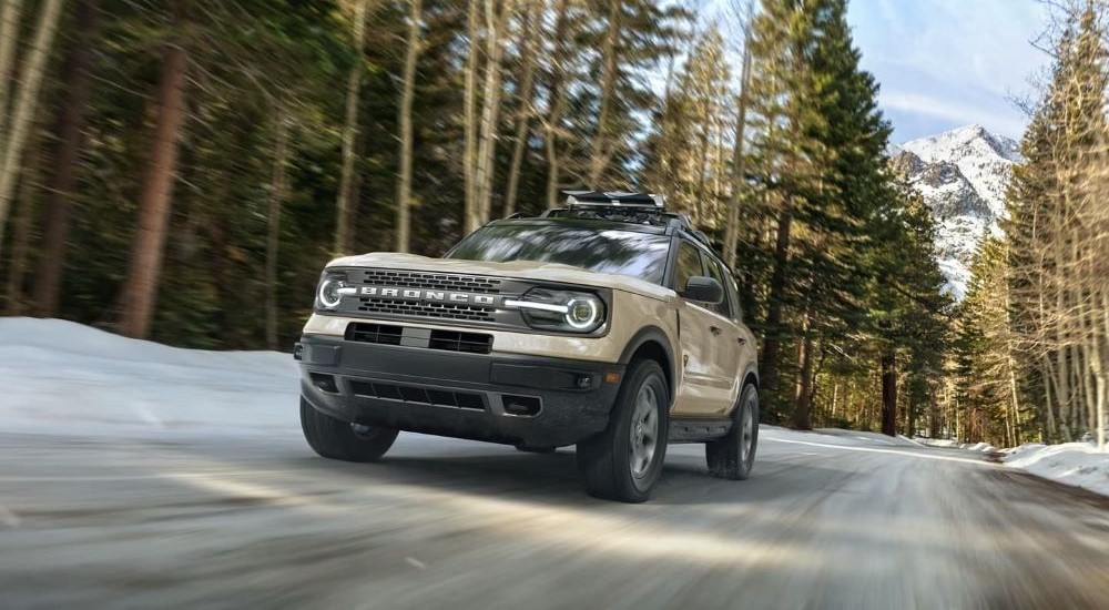 Tan 2025 Ford Bronco Sport Badlands driving off-road through a forest.