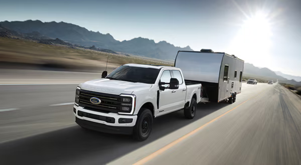 White 2026 Ford F-350 towing a camper to a Ford dealer near Elgin
