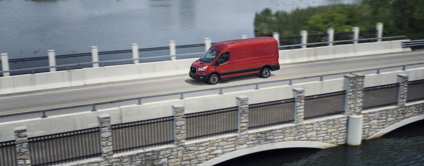 A red 2023 Ford Transit crossing a bridge.