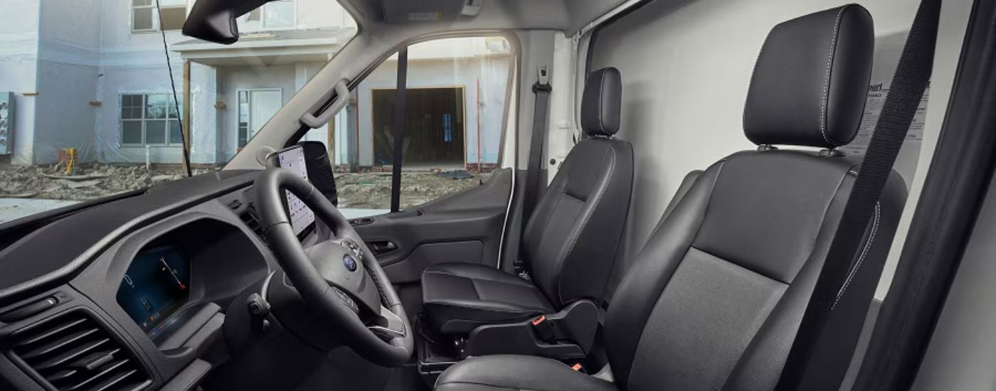 Interior view of a 2026 Ford Transit steering wheel and front seats.