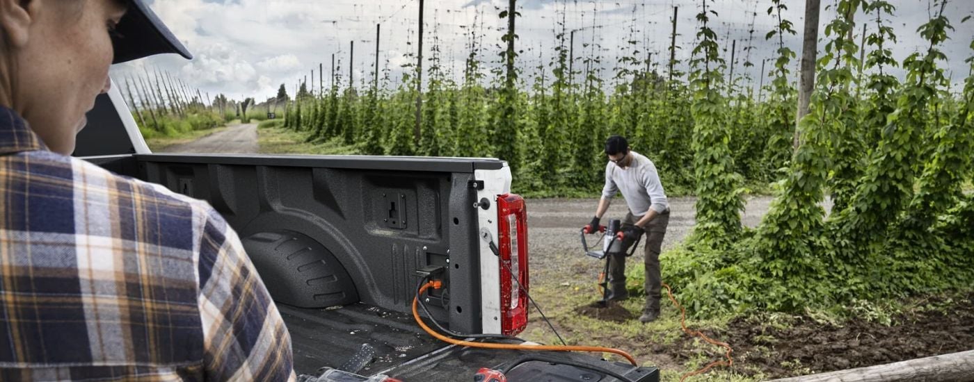 A person is shown using an auger near a white 2023 Ford F-350 XLT.