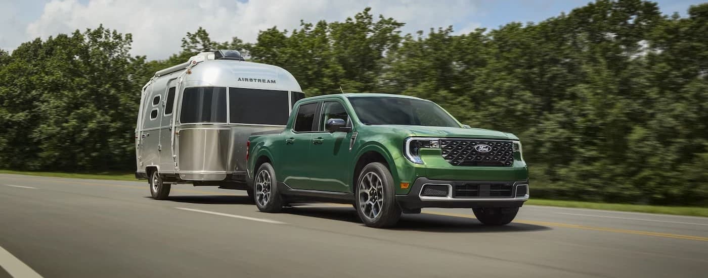 A green 2025 Ford Maverick towing a trailer.