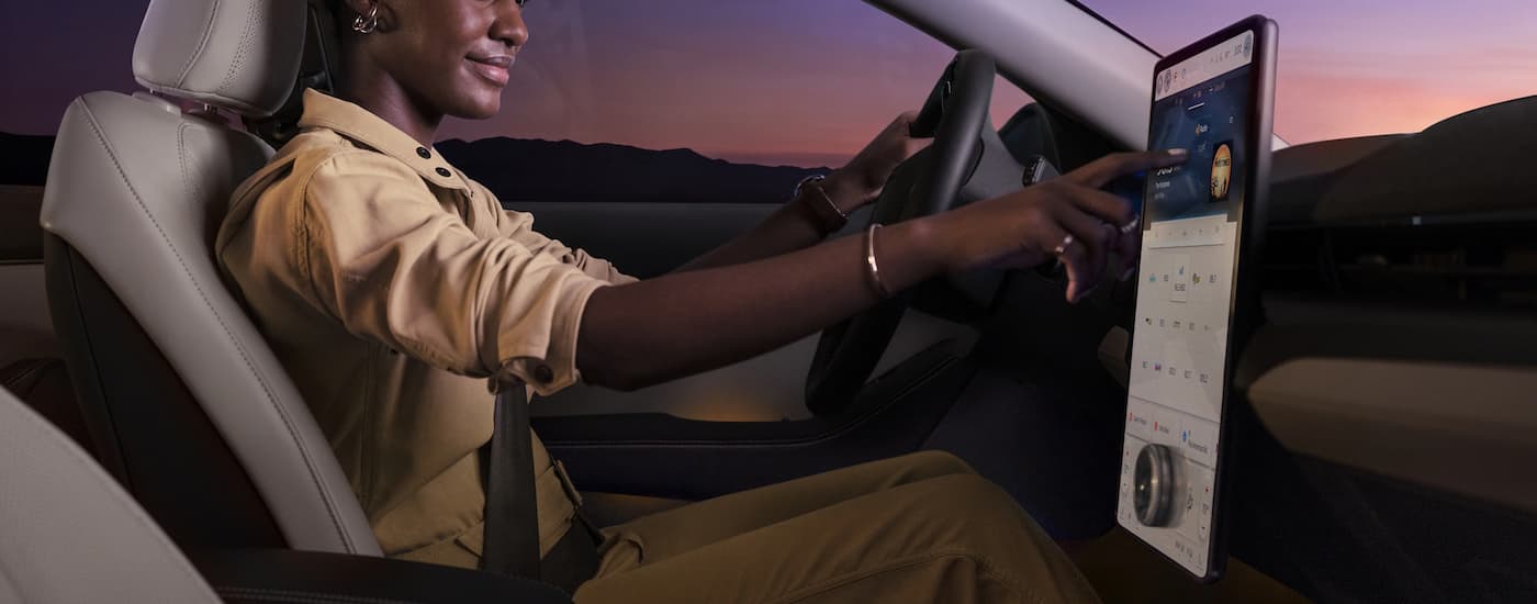 A woman is using the infotainment screen in a 2023 Ford Mustang Mach-E, a popular used Ford.