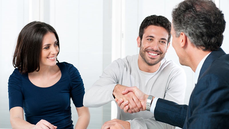 A man and woman shaking hands with salesperson